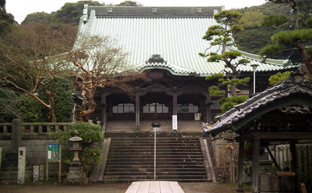 A large wooden temple hall at the top of stone steps