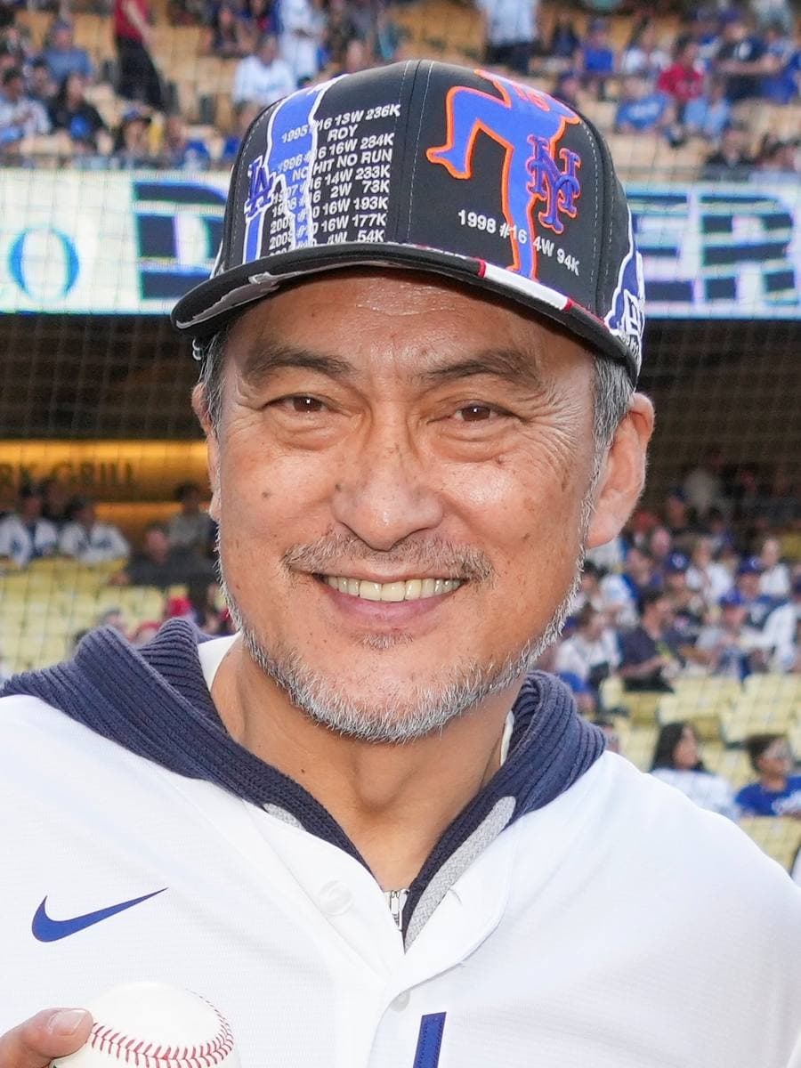Ken Watanabe smiling in a baseball cap