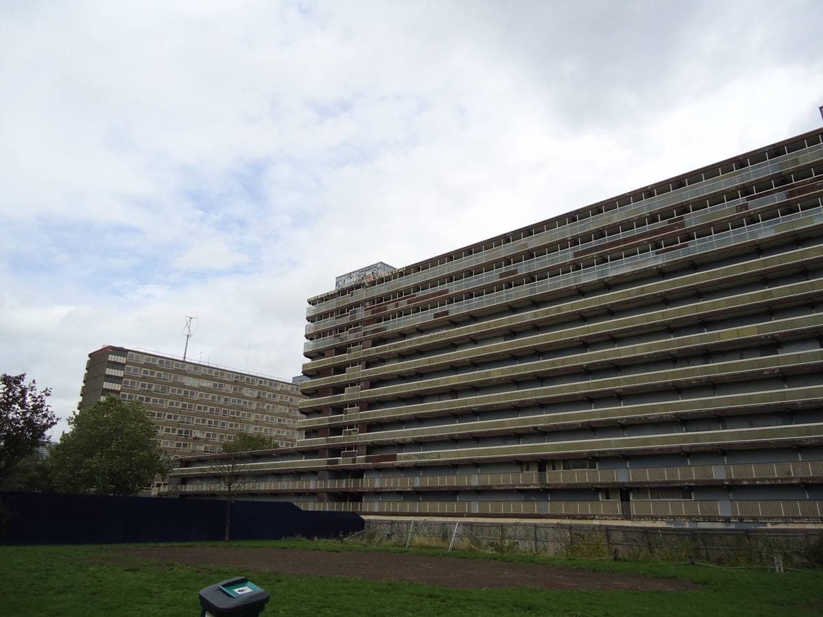 Long concrete slab blocks of flats with walkway decks, seen across open ground