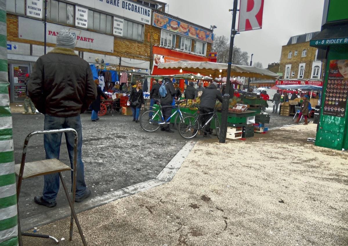 A street market with stalls under awnings, shoppers walking between them