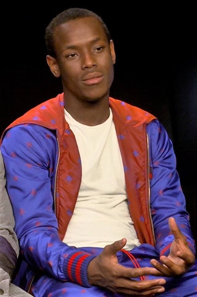 A young man in a dark top sitting for an interview