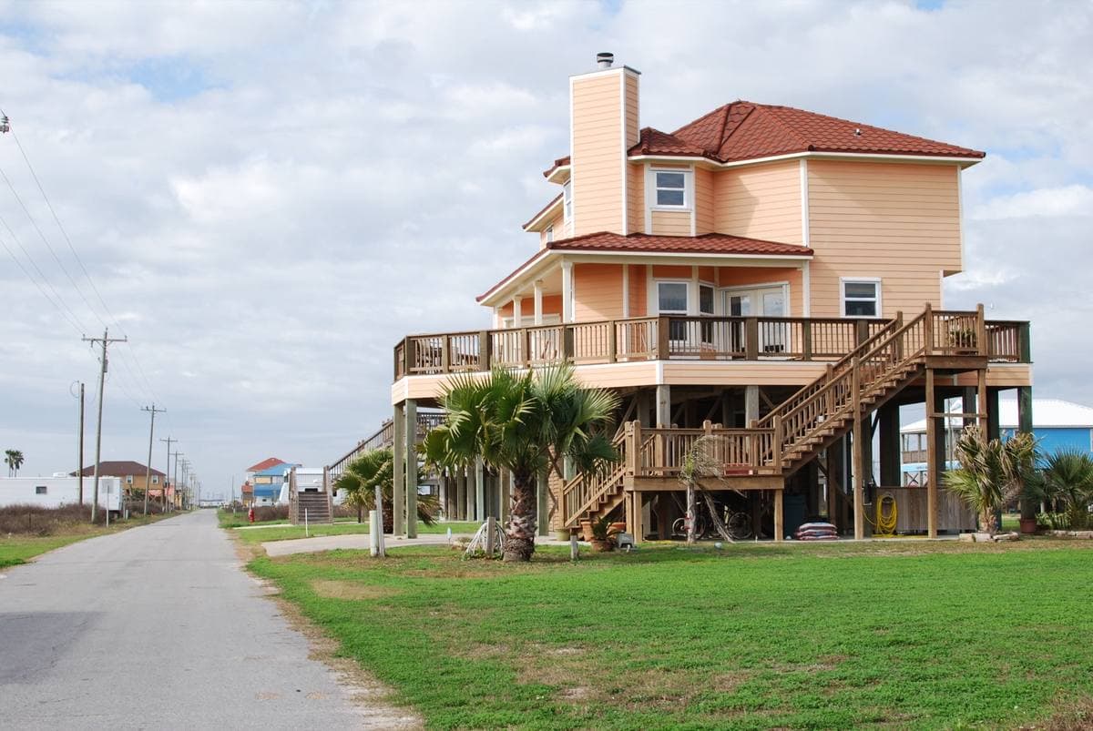 A raised beach house on stilts beside a narrow road