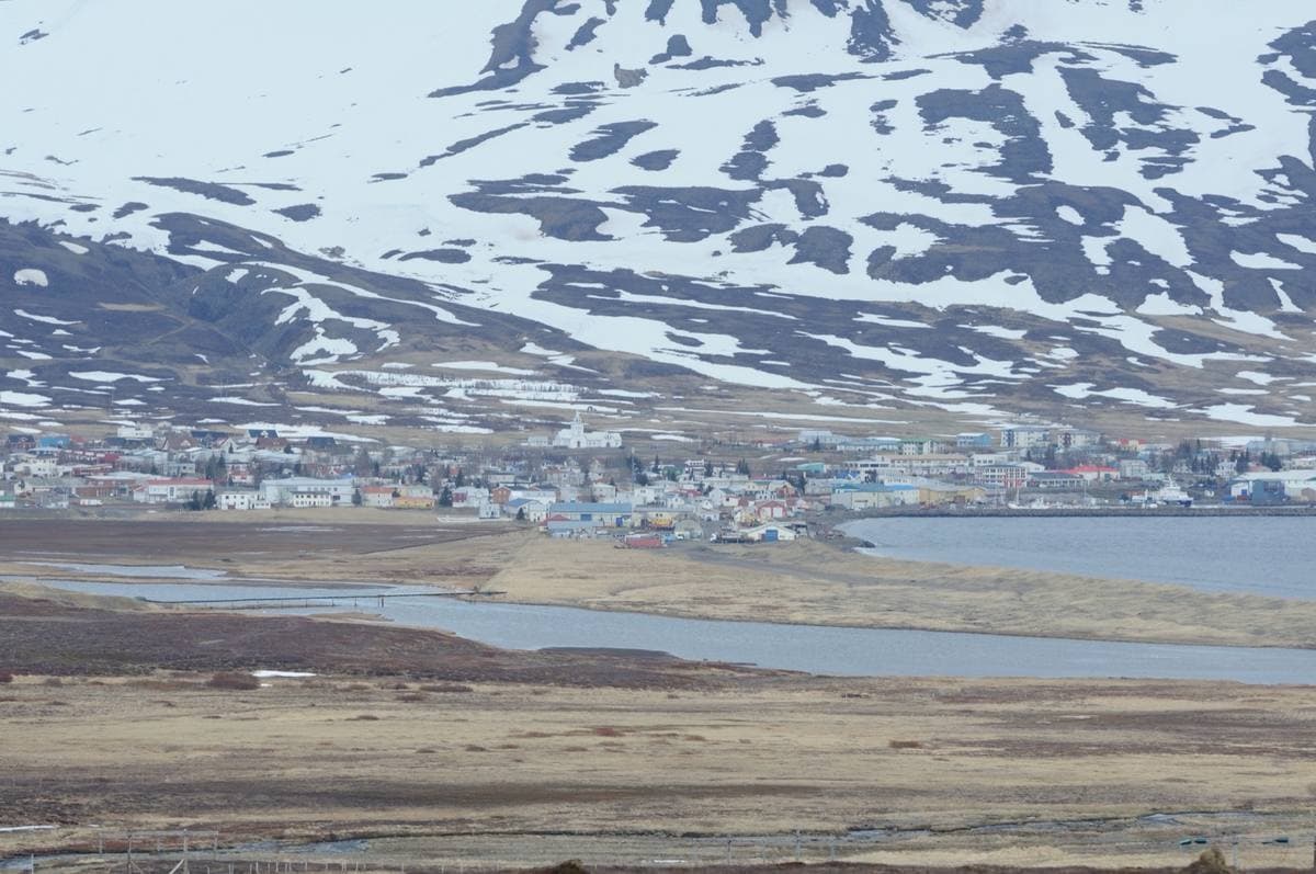 A small coastal town below snow-streaked mountains
