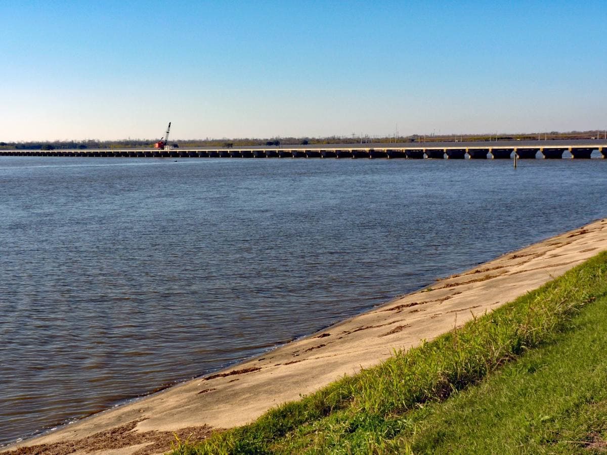 A long low concrete spillway across flat water under a clear sky