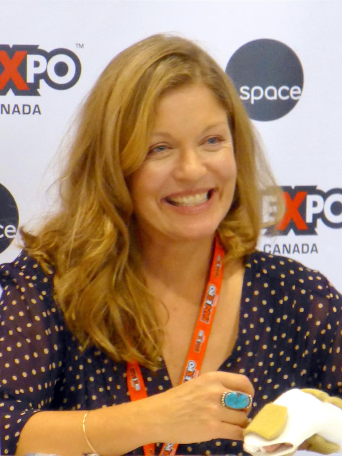 Sheryl Lee smiling at Fan Expo Canada, with an event lanyard and backdrop.