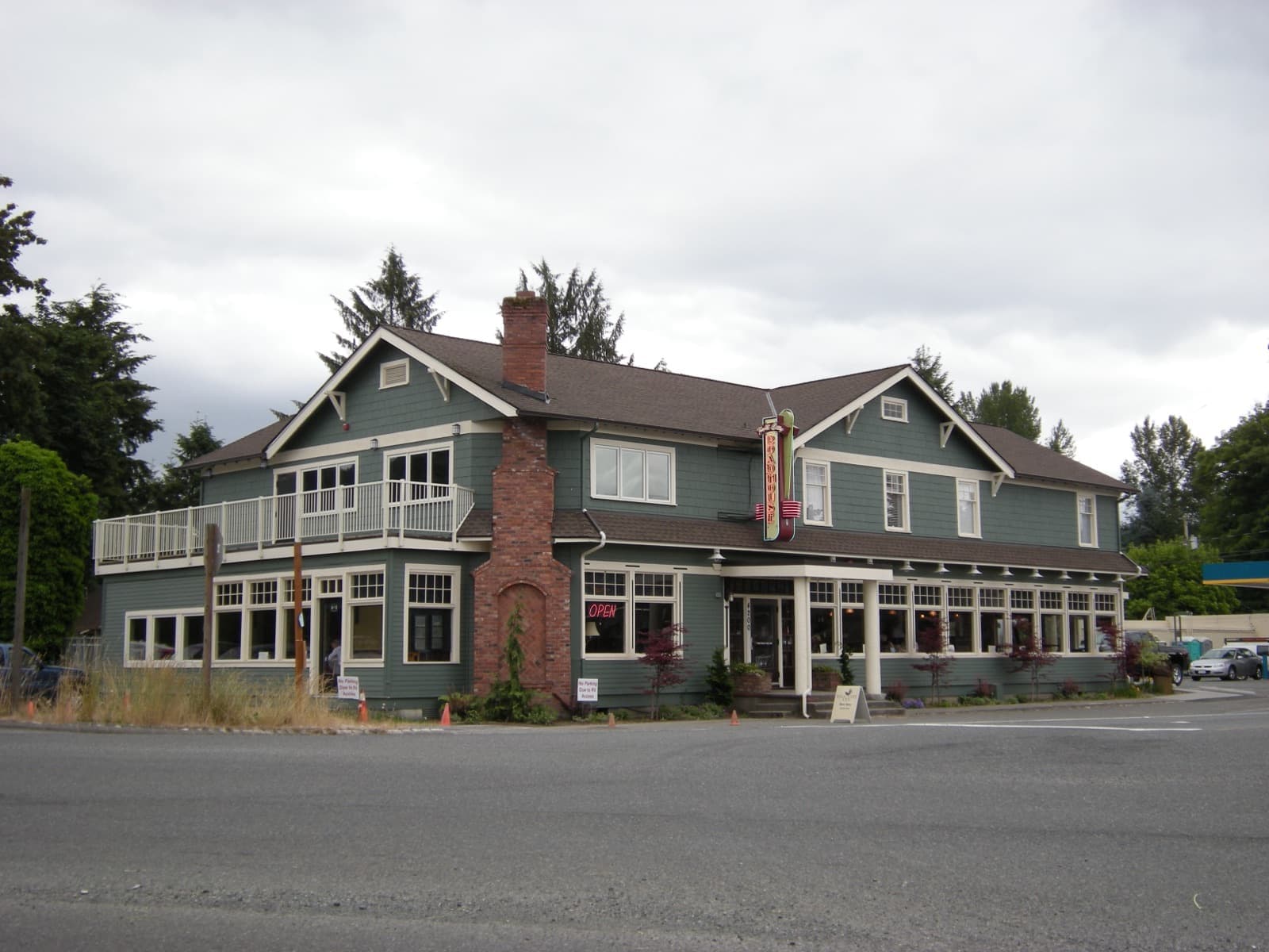 Two-storey grey Roadhouse building with brick chimney, balconies and roadside signage.