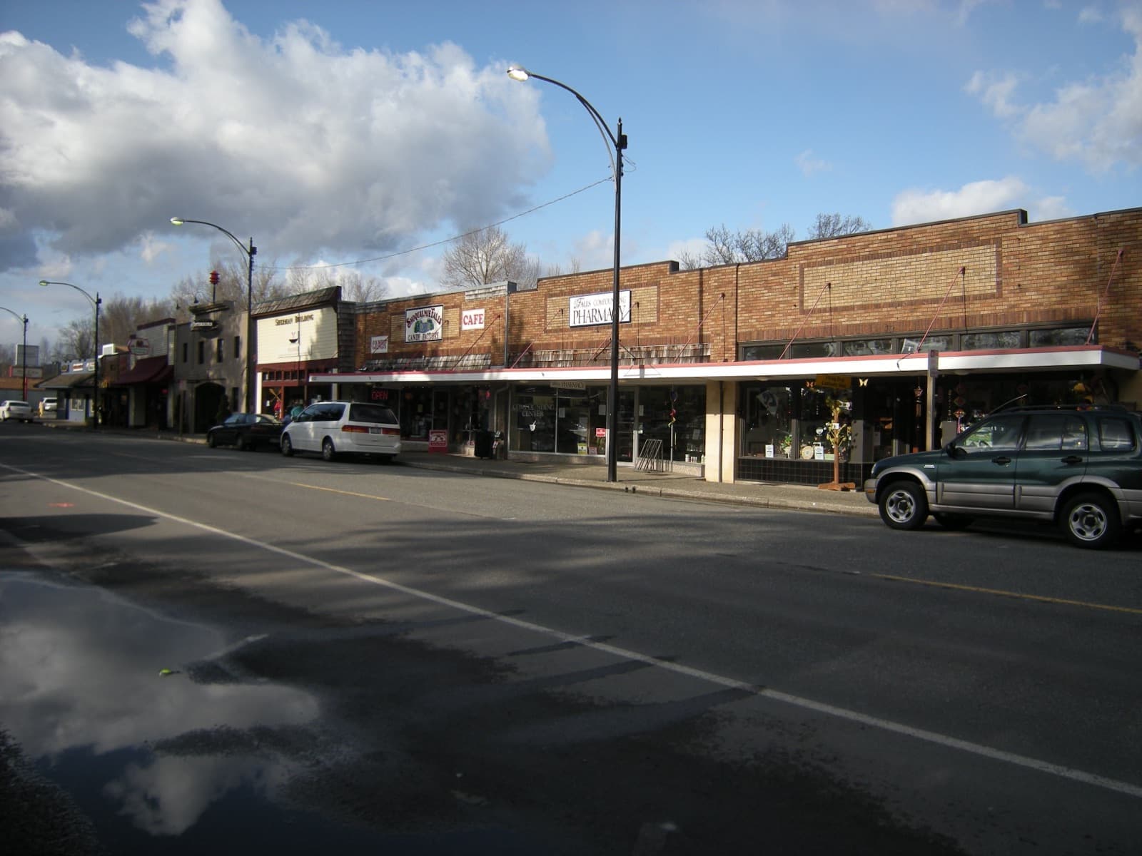 Brick shopfronts and parked vehicles on a downtown Snoqualmie street under a cloudy sky.
