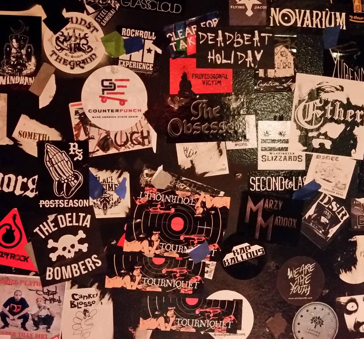 A wall covered in band stickers in black, white and red