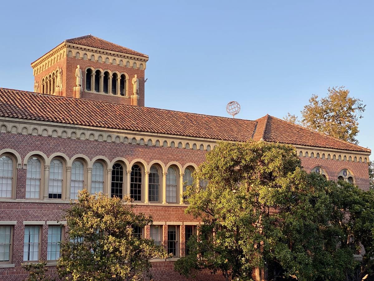 A brick Romanesque hall with a tower lit by low sun