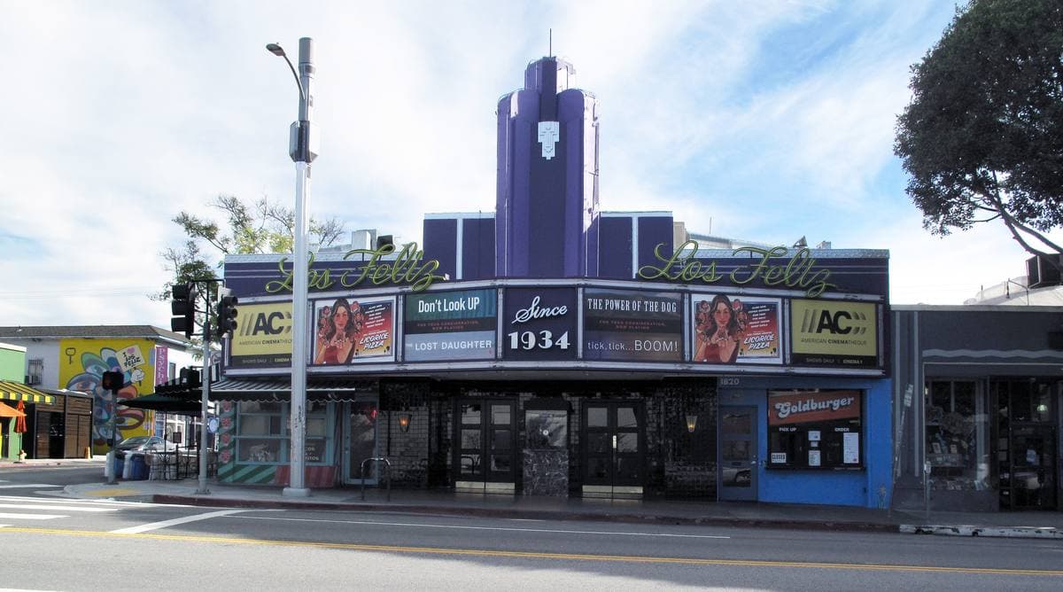 A streamline-style cinema with a tall blue sign on a sunny avenue