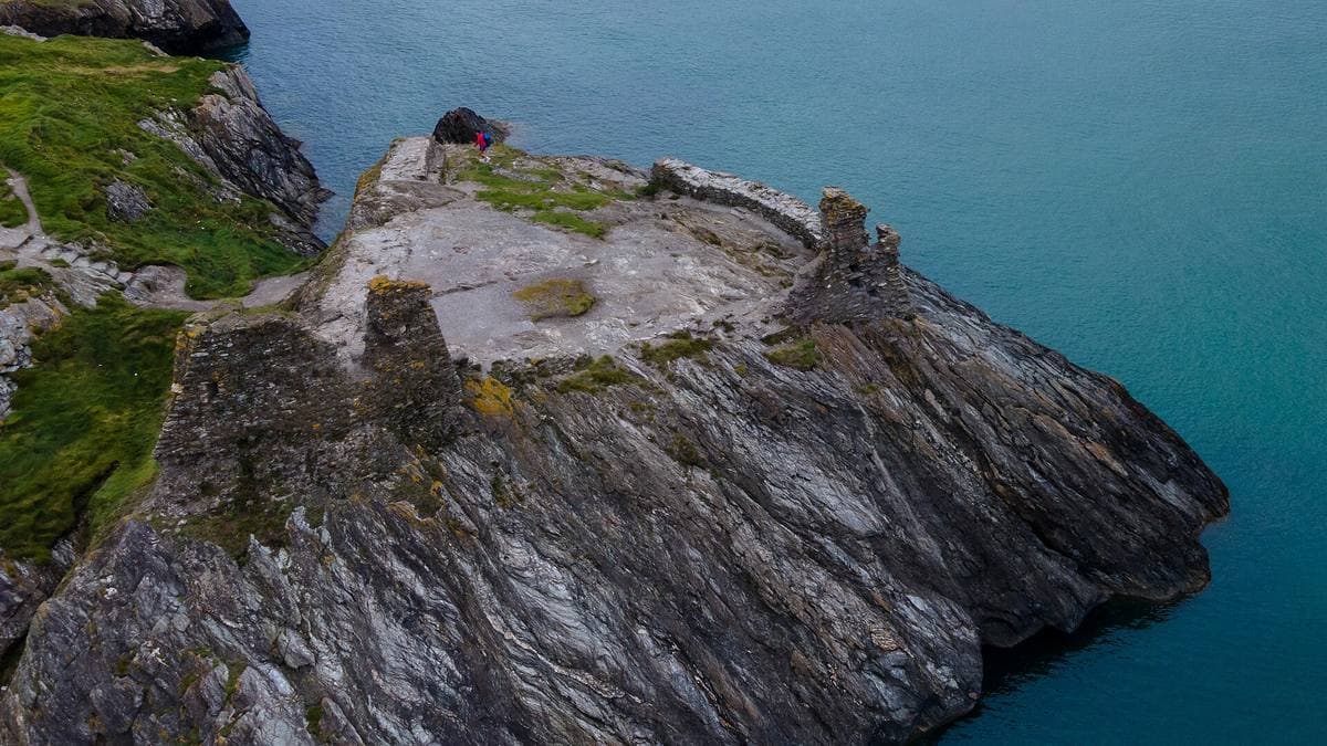 Ruined walls on a rocky point above blue sea