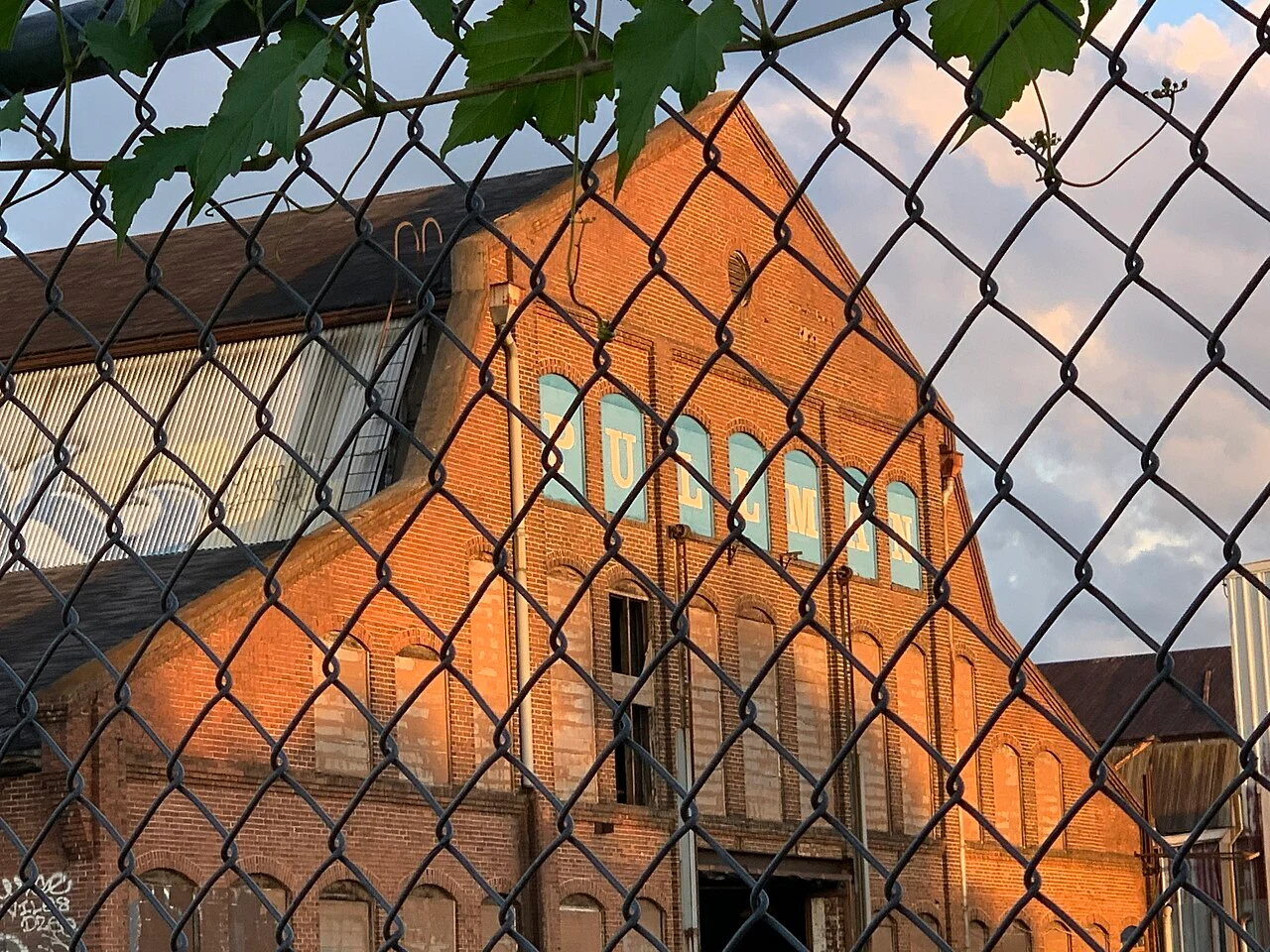Brick Pullman Yard industrial building behind a chain-link fence in 2020