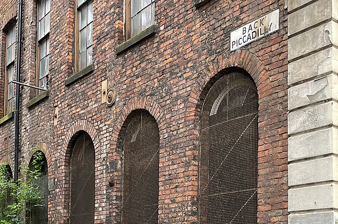 Back Piccadilly street sign above historic brick arches in Manchester