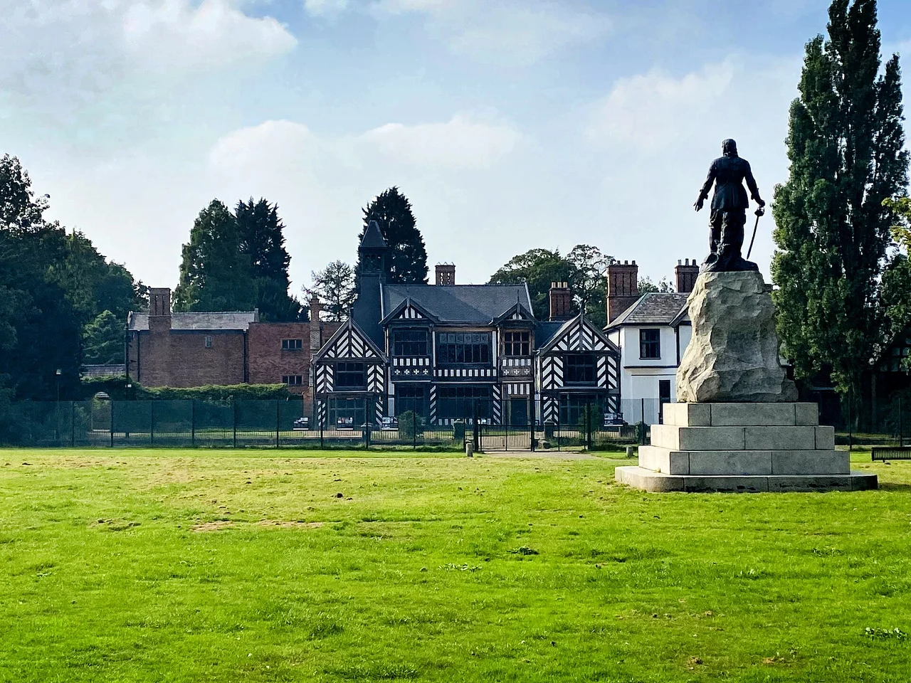 Wythenshawe Hall beyond its lawn, with the Cromwell statue in the foreground, 2021