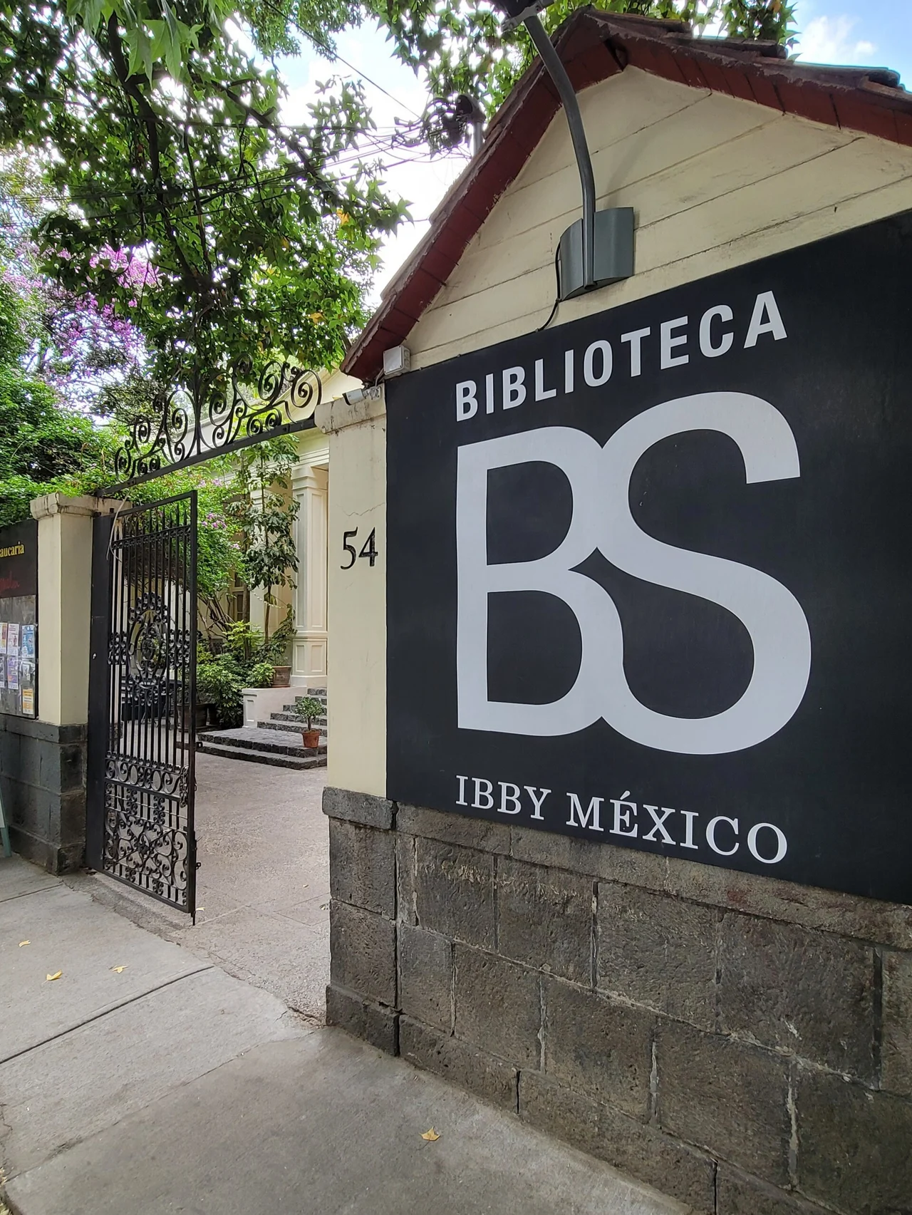 Named BS-IBBY México library entrance on a tree-lined street