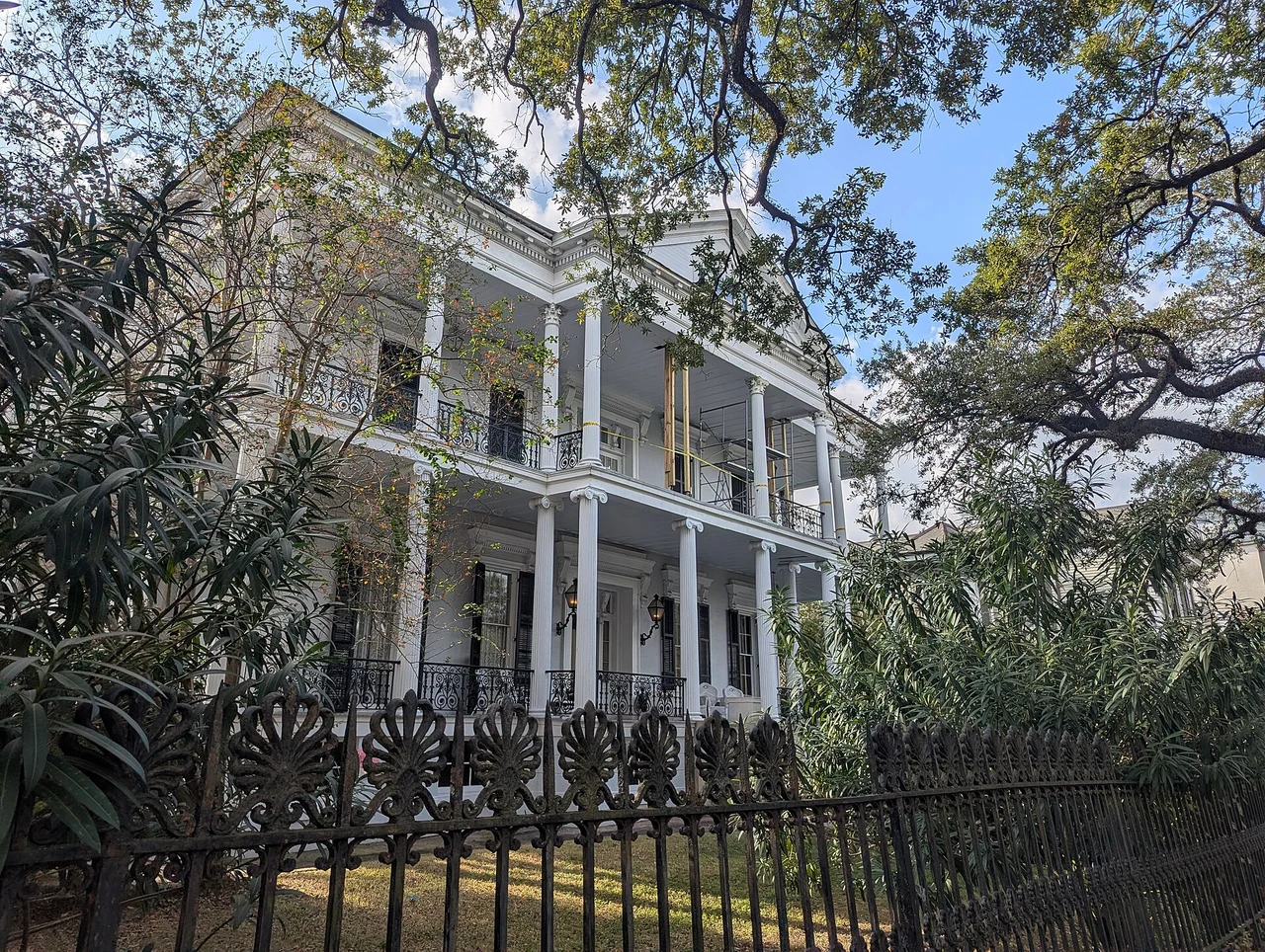 Columned galleries of Buckner Mansion behind its fence and trees