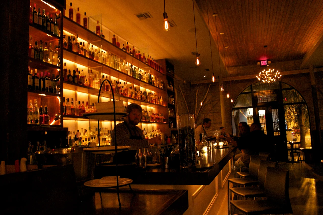 Cure’s bar interior with illuminated shelves and wooden bar stools
