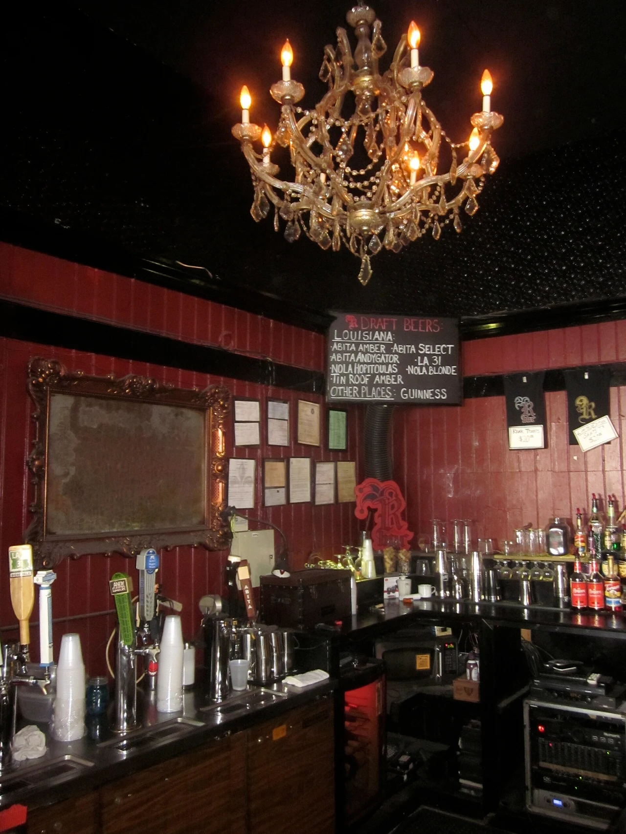A chandelier above the red-walled bar counter inside R Bar.