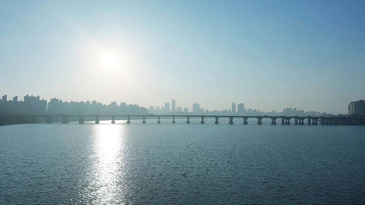 The long, low span of Jamsil Bridge across the Han River in hazy afternoon sun, seen from the Jamsil Railway Bridge