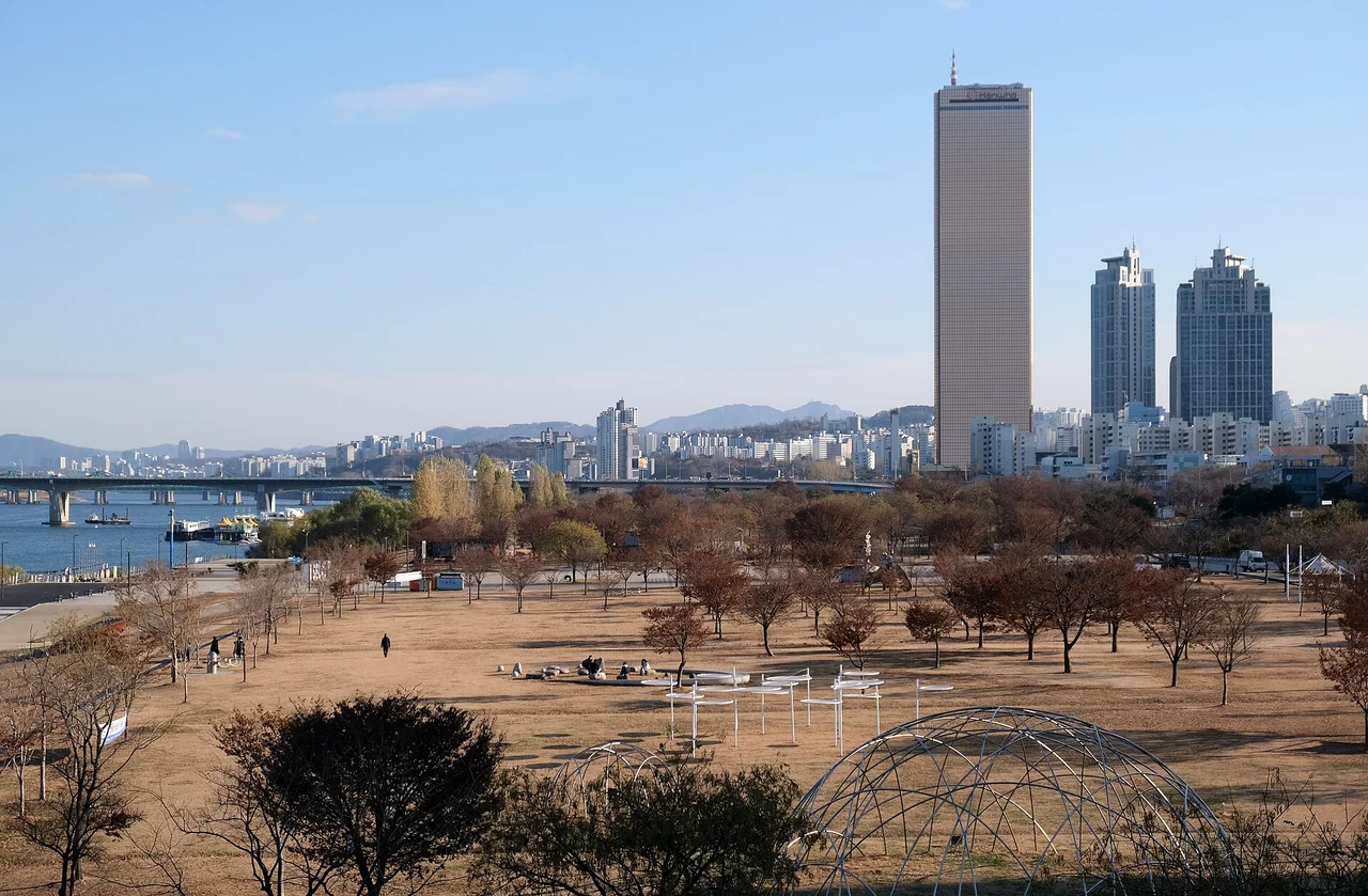 Winter paths, trees and open riverside park at Yeouido in 2022, with the city skyline behind