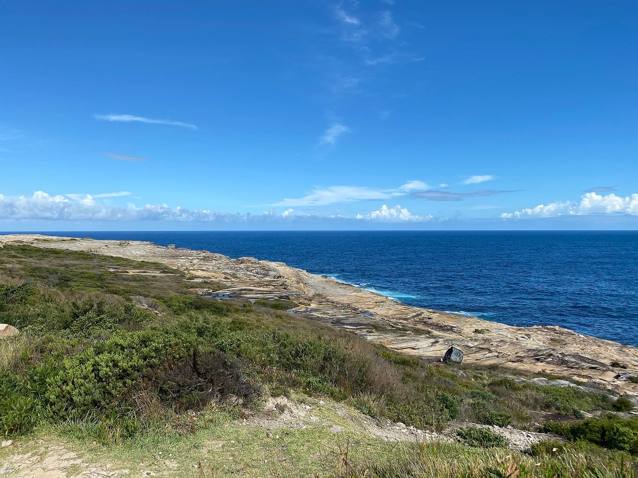 Low coastal scrub and sandstone shelves at Boora Point beside the blue ocean
