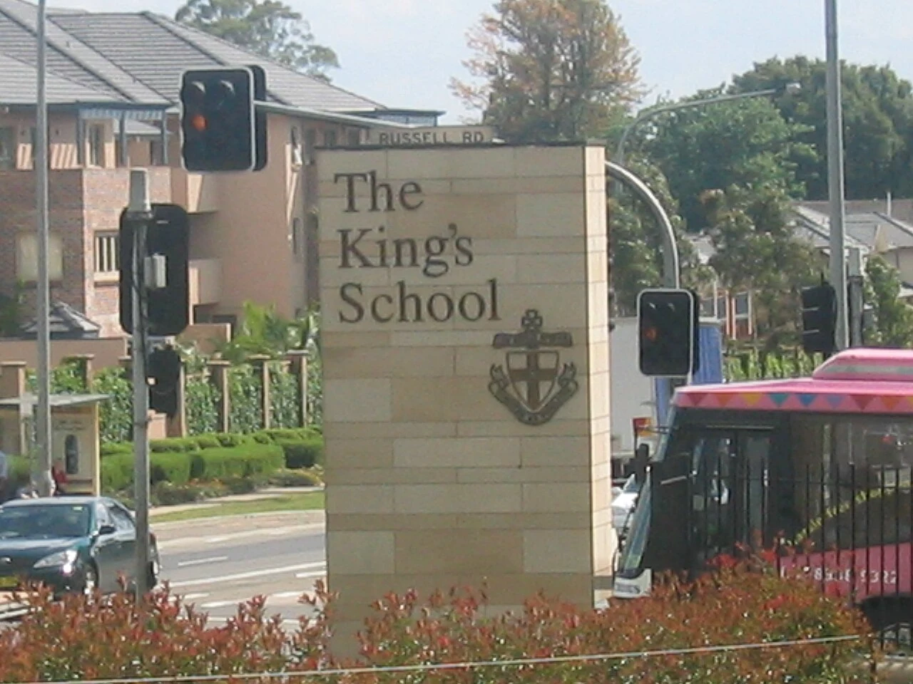 The King’s School entrance sign in Parramatta beside a road and bus