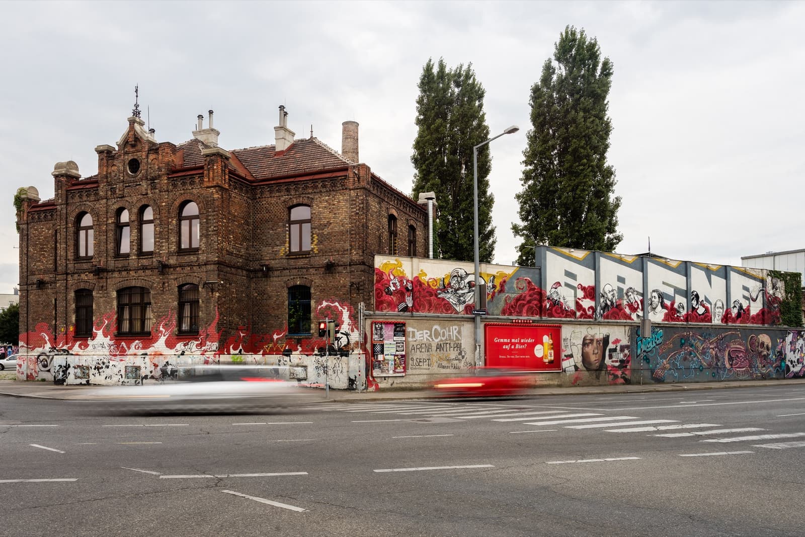 A red-brick hall behind a graffiti-covered wall