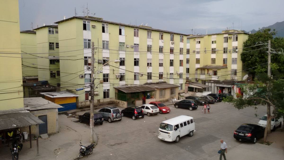 Low rooftops and streets of Cidade de Deus spreading towards green hills