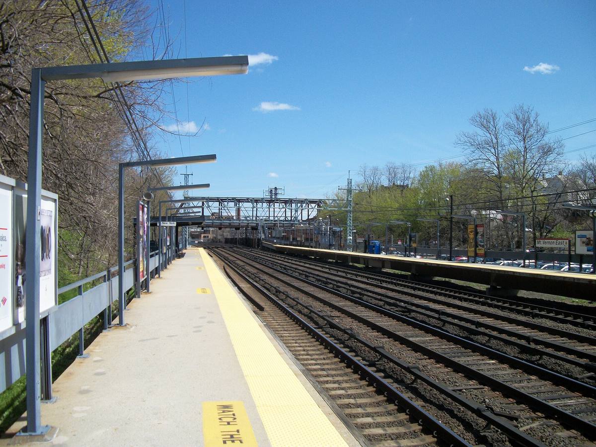 A long railway platform with a yellow edge beside four tracks