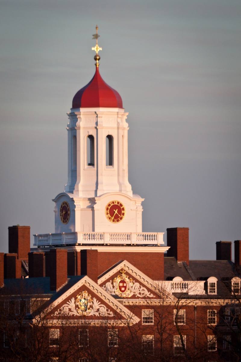 The white clock tower and red cupola of Dunster House at sunset
