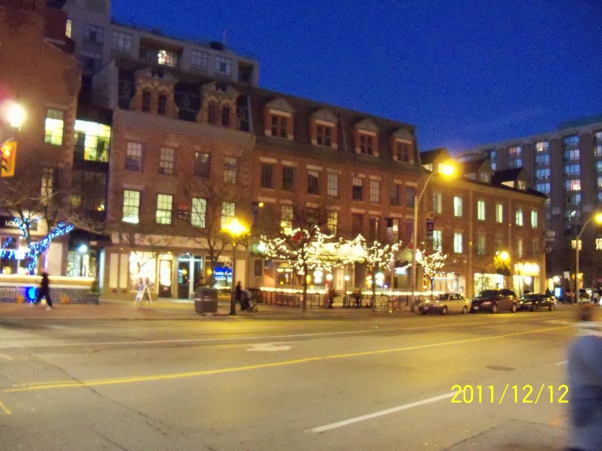 Lit shopfronts along Front Street East at dusk
