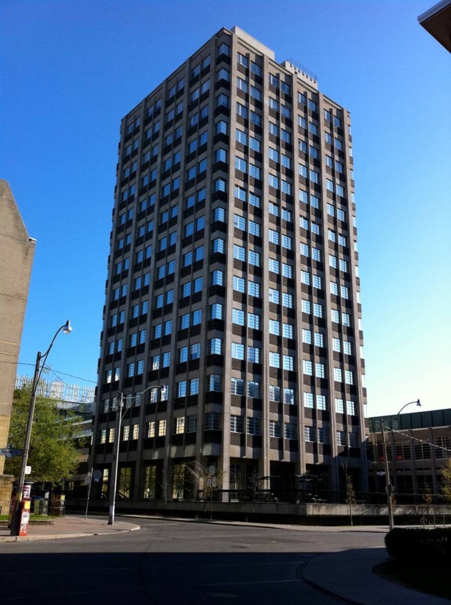 A dark concrete tower block against a blue sky