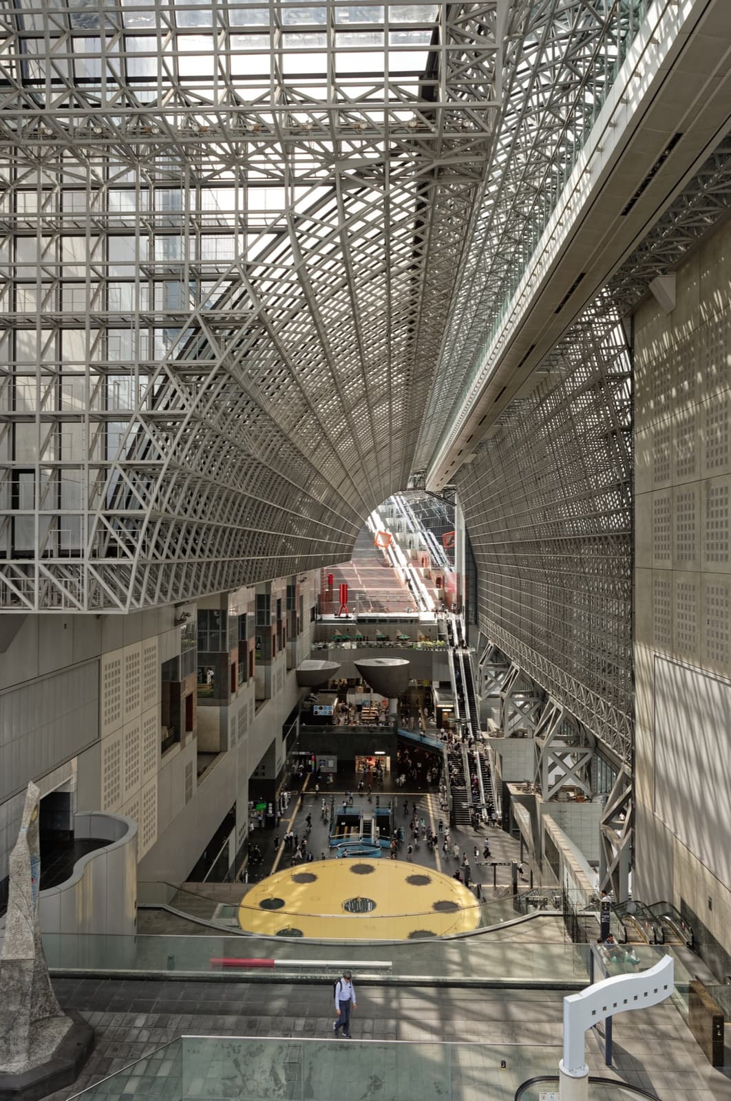 A long glass and steel atrium with escalators climbing away