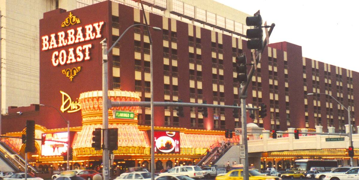 A red-brick hotel with a lit BARBARY COAST sign on a busy corner