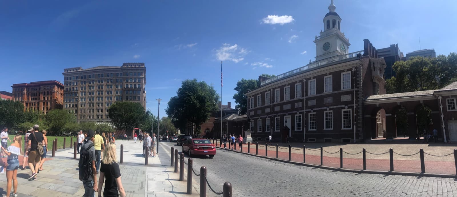 Independence Hall’s brick front and clock tower beside Chestnut Street, with people on the pavement