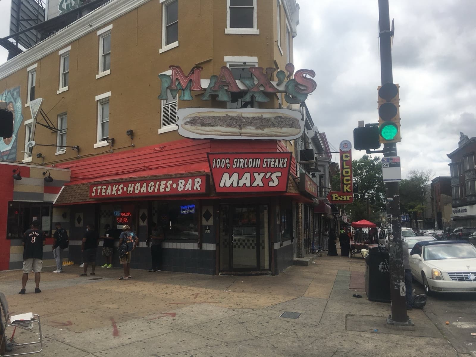 Max’s Steaks on a street corner, with a red neon sign and a red awning