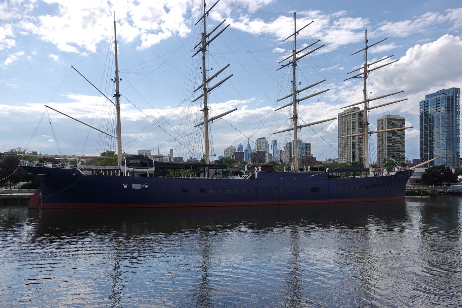 The four-masted ship Moshulu moored on the Delaware, with towers behind