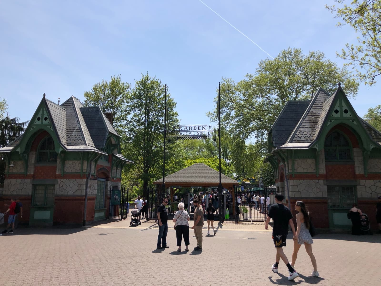 Two Victorian gatehouses at the Philadelphia Zoo entrance, with visitors walking between them