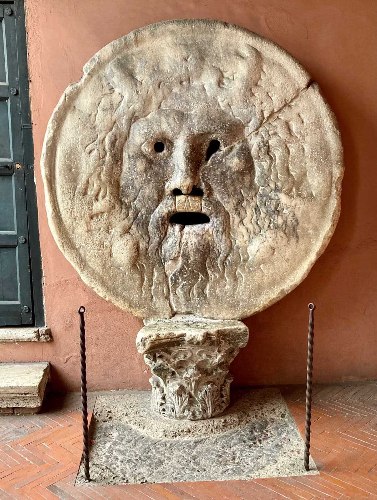 The round stone face of the Bocca della Verità against a brick wall