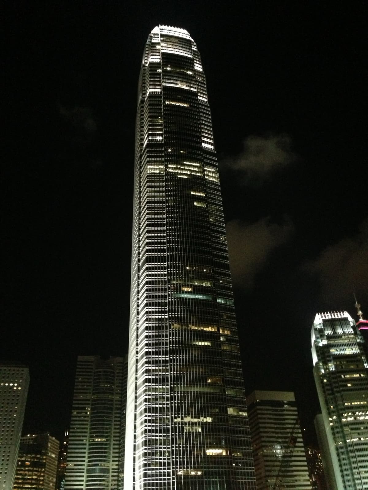 A tall lit skyscraper with a crown of fins against a black sky