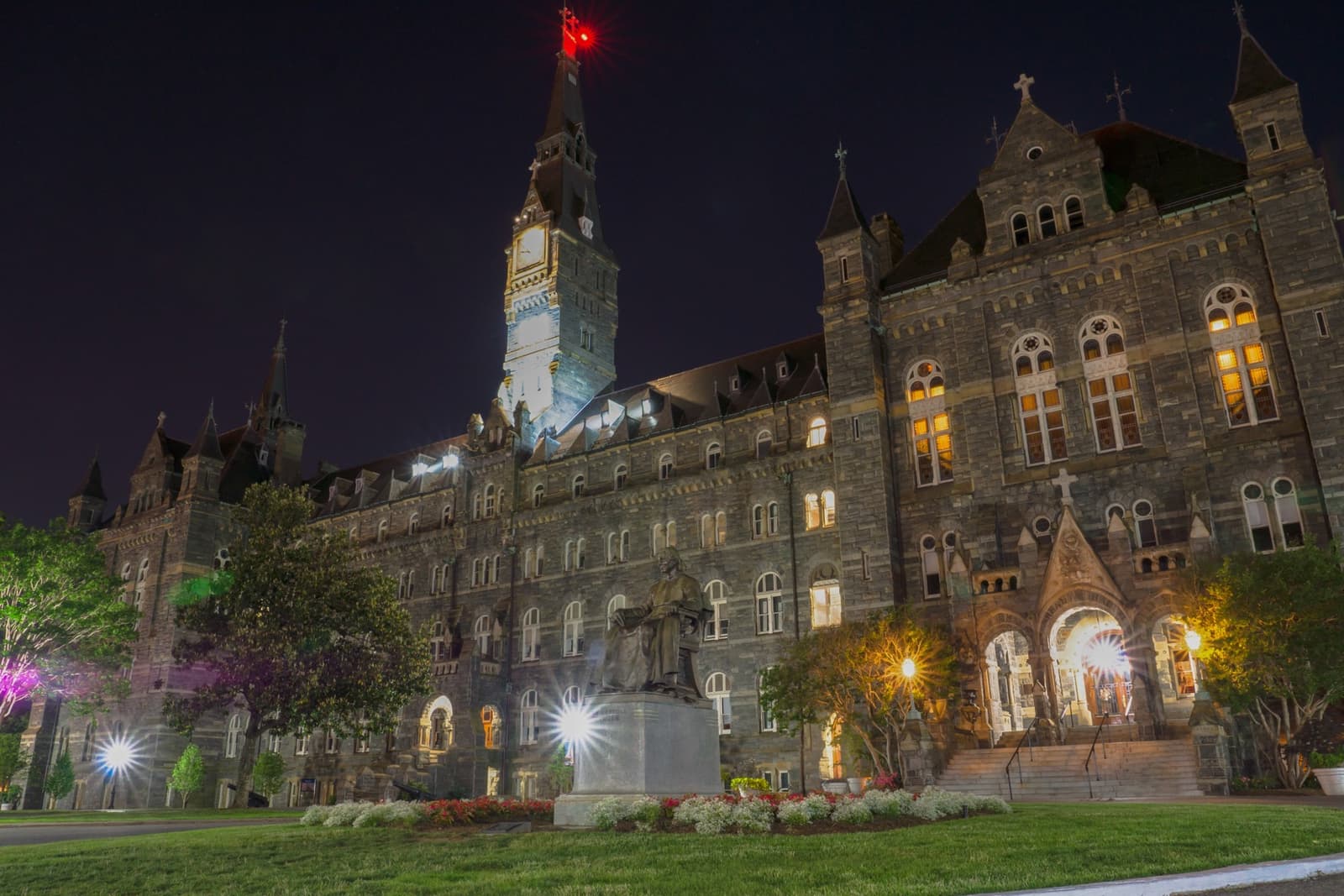 The dark stone towers and spires of Healy Hall lit against a night sky