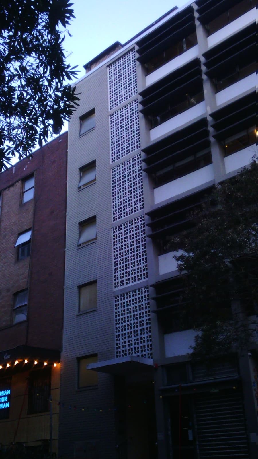 A pale six-storey building with a screen of patterned breeze blocks down one side