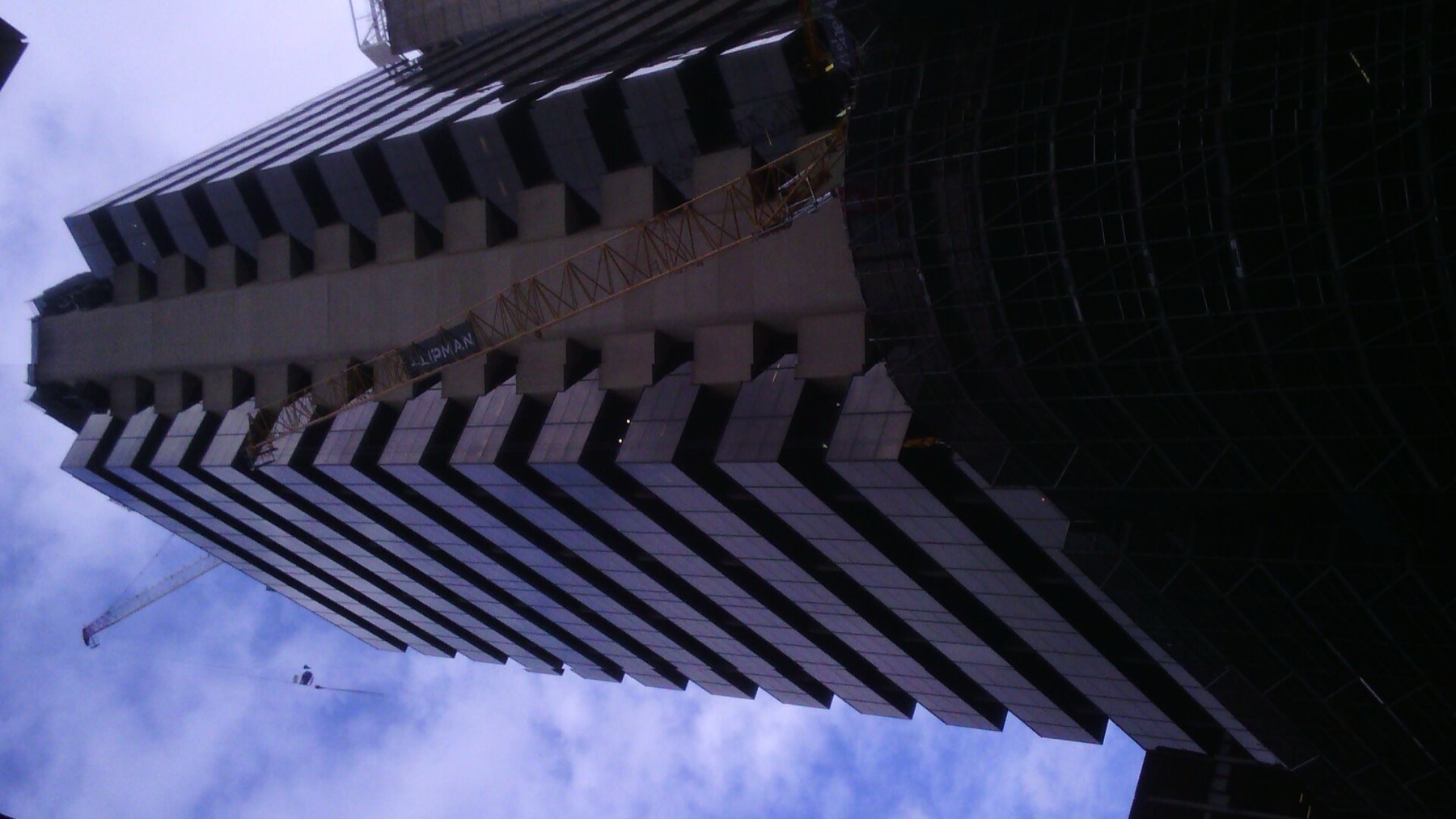 A dark office tower with stepped balconies against a blue sky
