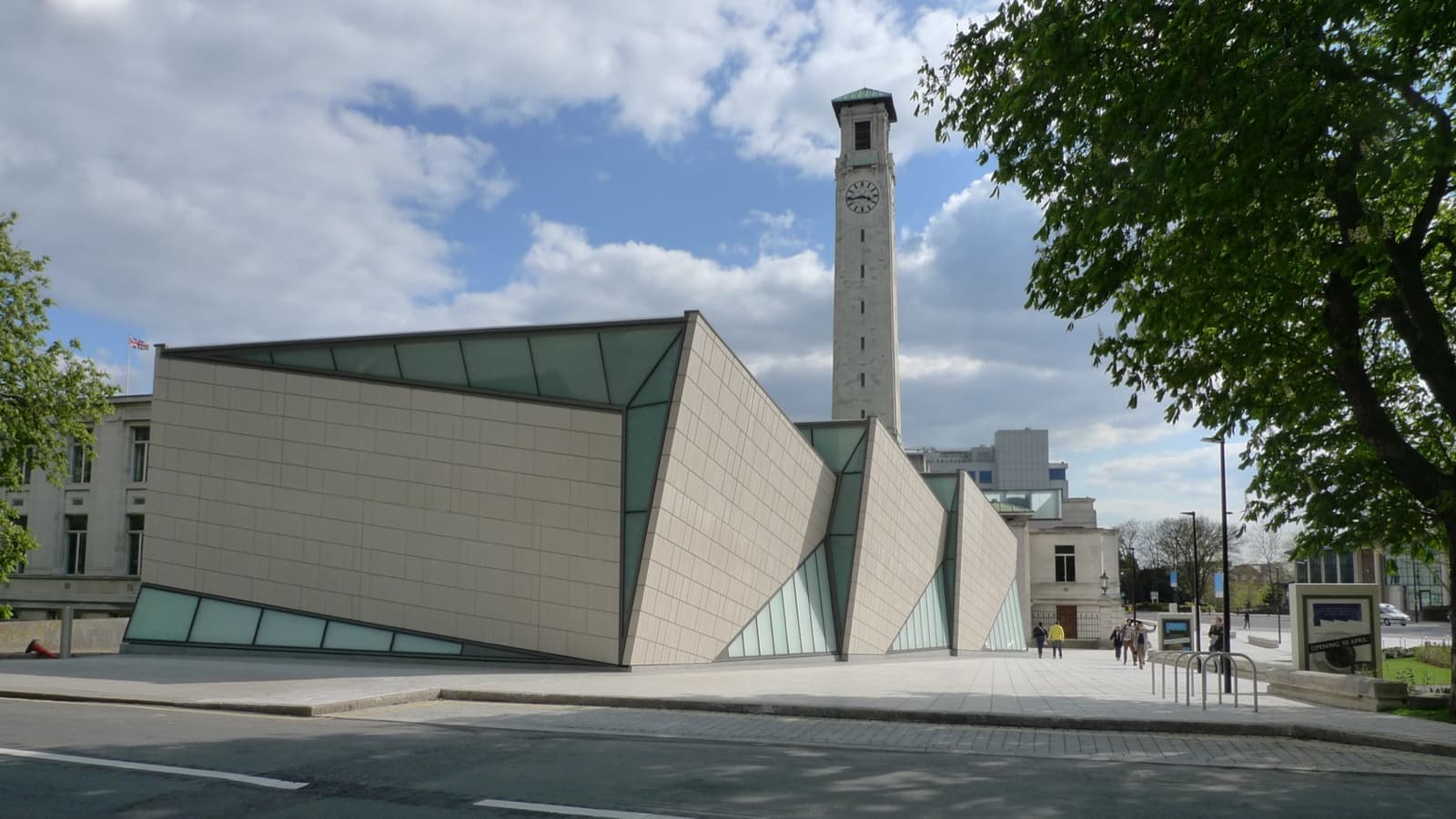 A modern pavilion beside a stone clock tower