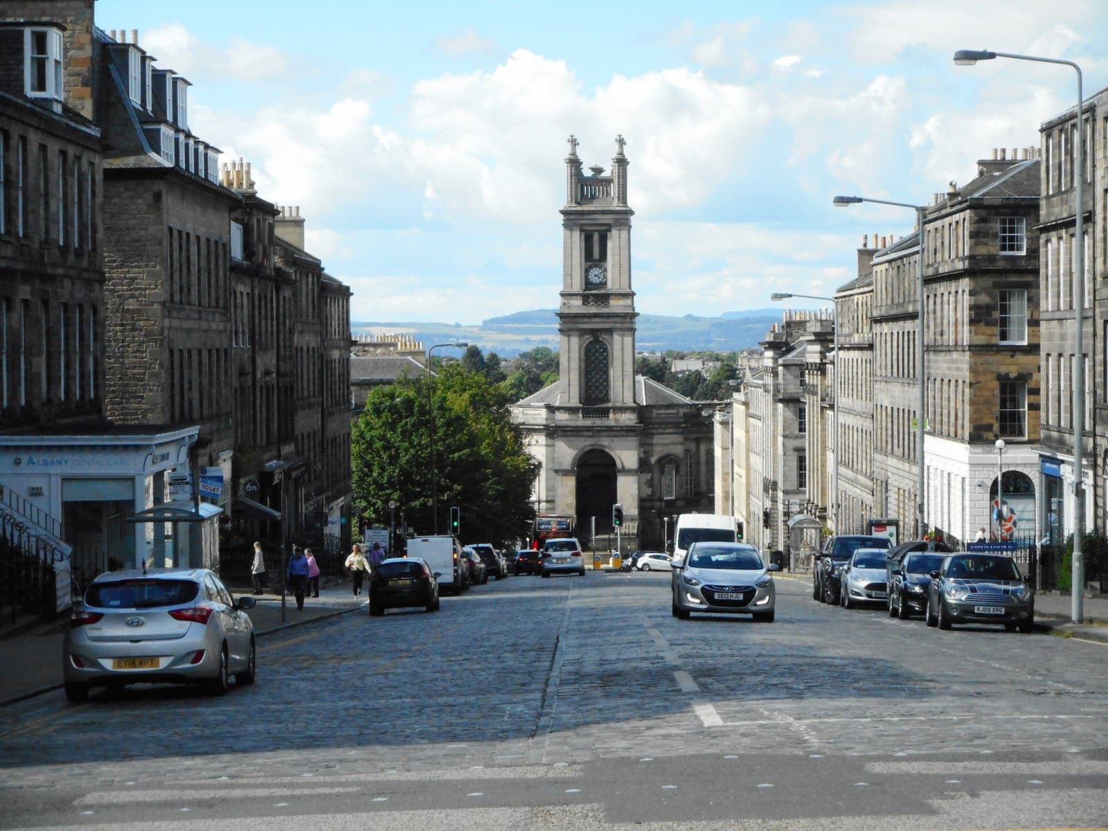 A tall stone church tower closing the view down a sloping New Town street