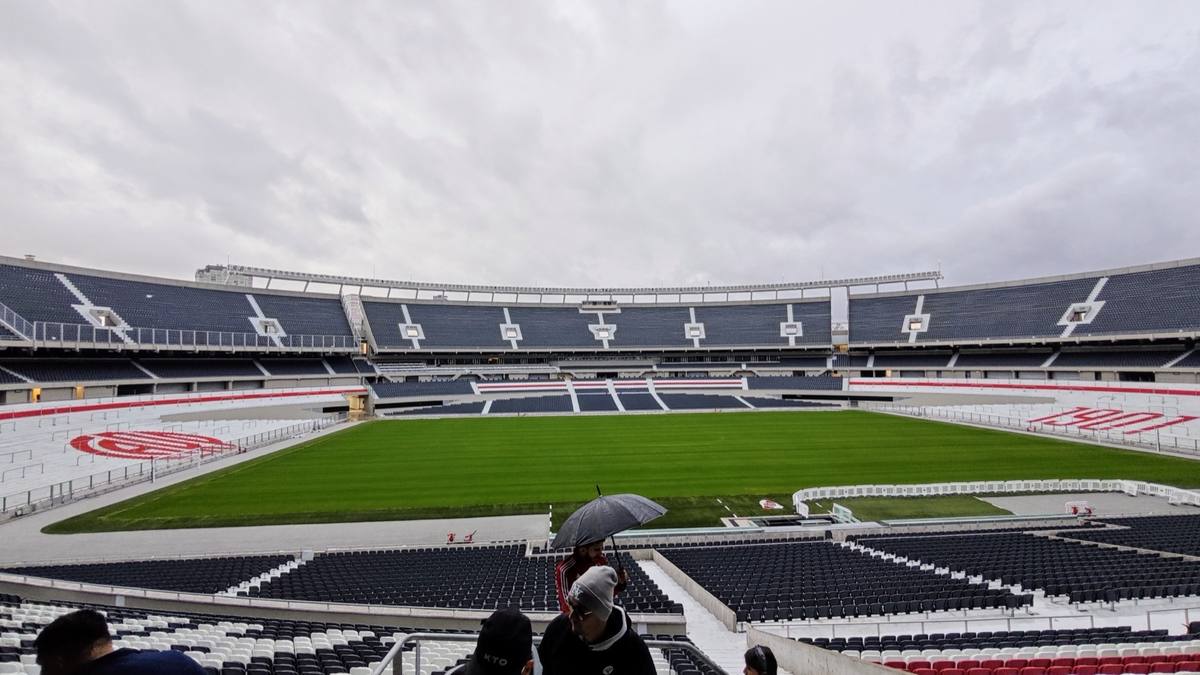 A big stadium bowl of red and white seats around a green pitch