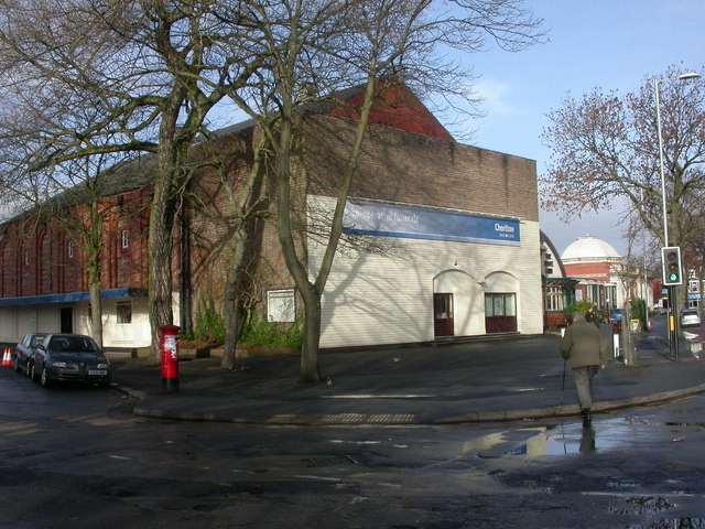 A red-brick former cinema with a pale modern front on a street corner, under bare trees