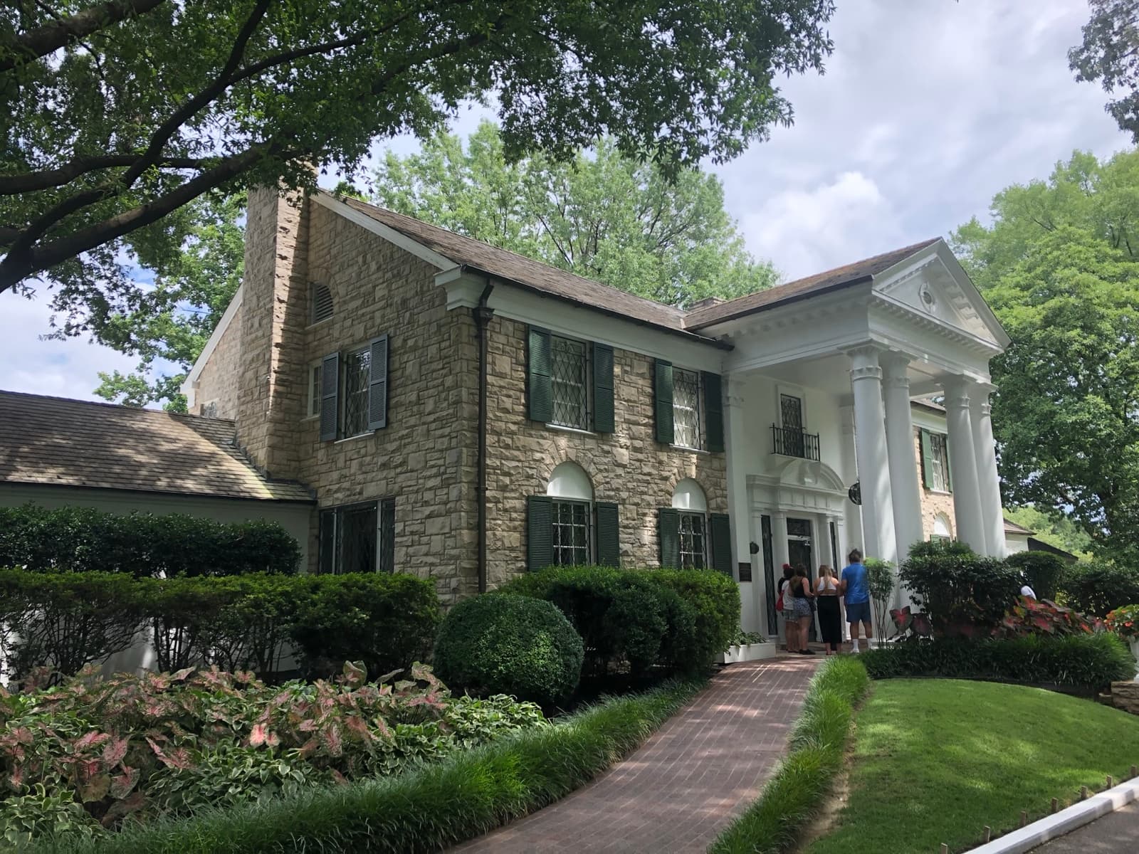 A white-columned mansion behind a lawn and trees