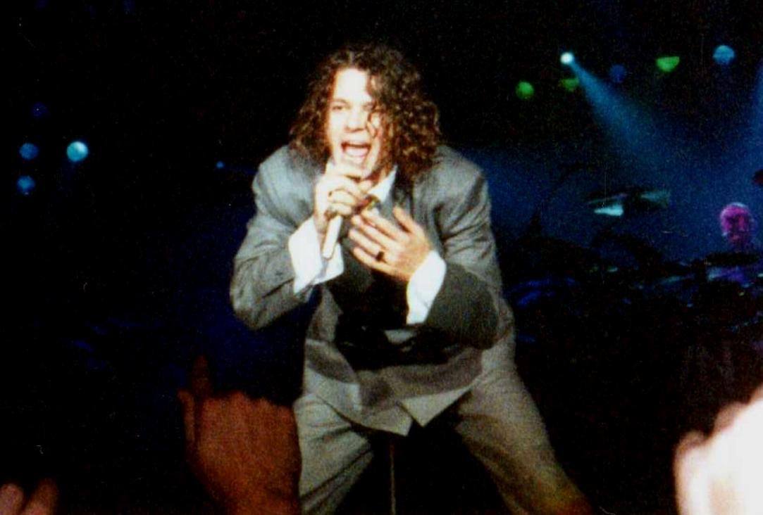 Michael Hutchence singing on a lit stage in Madrid in 1990