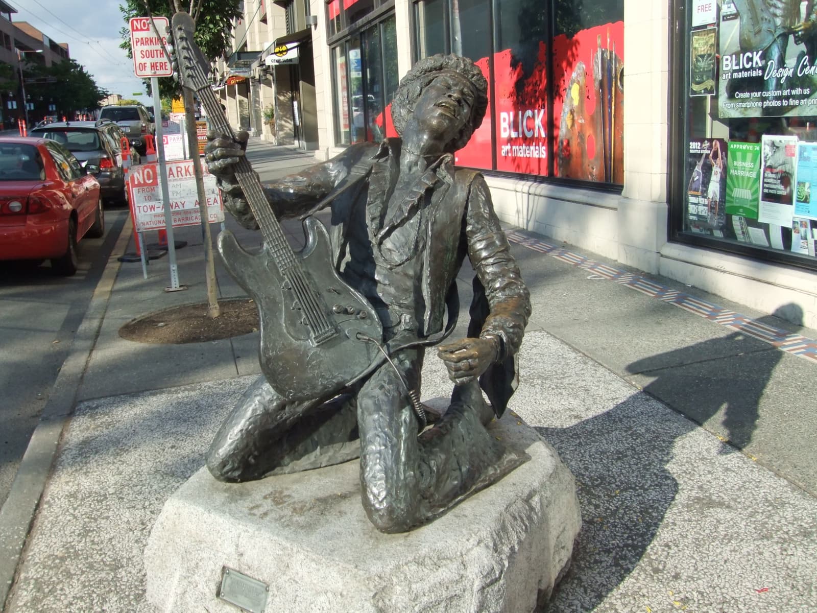 A bronze kneeling figure of Hendrix with a guitar on a pavement